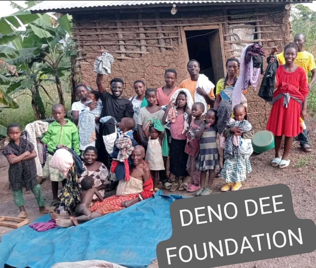 Foundation team with a family holding donated clothes outside a mud-brick home
